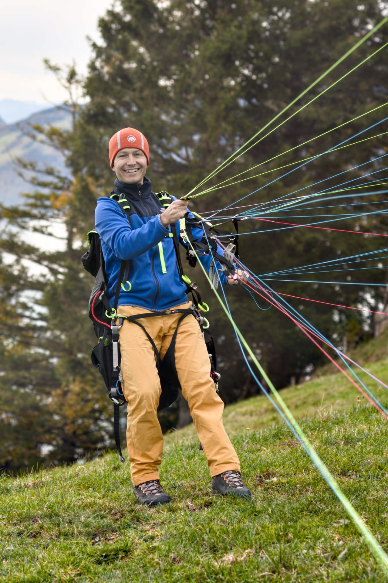 Tandem pilot Daro Flückiger inflates the paraglider at the launch site to sort the lines. He wears a broad smile as the canopy gently lifts into the sky.